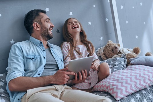 Haus-Vater-Tochter-Wohnen-Serie-4-15 Vater und Tochter schauen auf ein Tablet und lachen